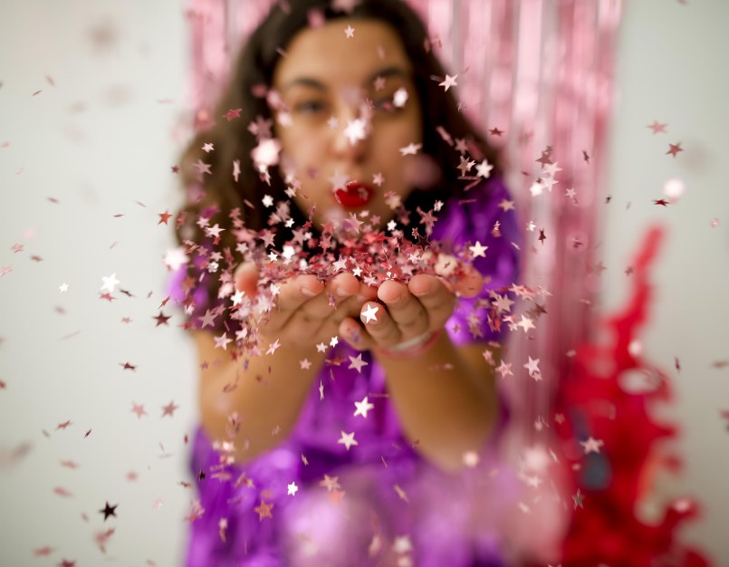 Taylor blowing star confetti toward the camera